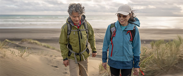woman and man walking on a beach in light jackets